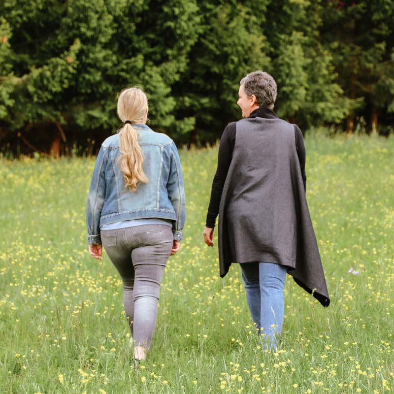 Walk und Talk | Angela Peichl – Angela mit Klientin unterwegs auf der Wiese in Richtung Wald